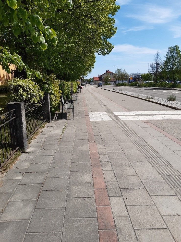 Markremsan som kommunen vill lösa in utgår ungefär från staketet till den röda gatstenen (Foto: Ljusdals kommun, 2023-05-30). 